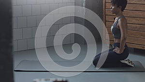 Closeup of mixed race african american woman makes a stretching routin on the floor in sunny loft