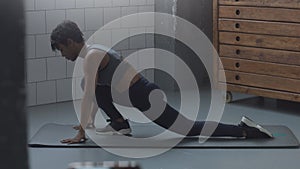 Closeup of mixed race african american woman makes a stretching routin on the floor in sunny loft