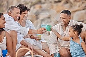 Closeup of a mixed race family having a picnic on the beach and smiling while having some food with snacks. Happy family