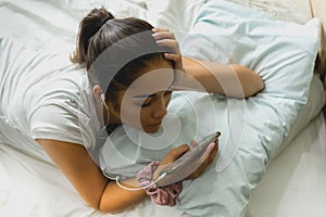 Closeup Mixed Race teenage girl lying in bed using cell phone.