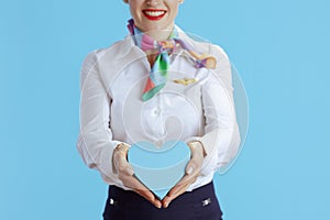 Closeup on modern air hostess woman on blue showing heart