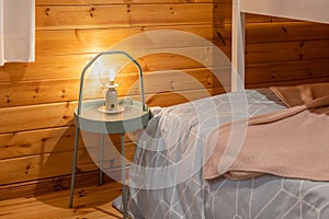 Closeup of modern bulb lamp on bedroom night table in a wooden room interior.
