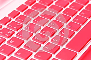 Closeup of a modern computer keyboard keys in red tones. Close up view of a business workplace with wireless computer keyboard. To