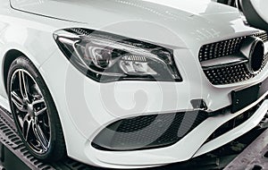 Closeup modern luxury white front lights headlight and head lamp rims of powerful sport car. Dealership office showroom sale hype