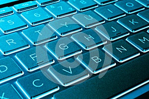 Closeup of a modern silver laptop computer keyboard. Laptop keyboard. Detail of the new and ergonomic computer keyboard. Blue tone