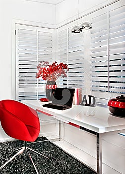 Closeup of a modern work room with a red chair a white table inc