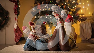 Closeup of mom and son in knitted wool socks lying on floor next to Christmas tree at house
