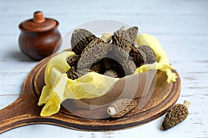 Closeup of morels in a box on a wooden board on a light background.