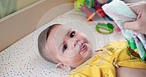 Closeup of mother cleaning face and eyes of her newborn baby son with cooton pad. Mother is wiping baby with wet cotton