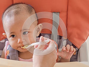 Closeup of mother feeding asian baby girl with a spoon in high c photo