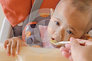 Closeup of mother feeding asian baby girl with a spoon in high c photo