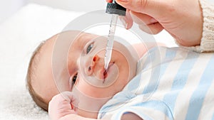 Closeup of mother giving vitamin D and K to her newborn baby son from eyedropper. Concept of babies and newborn