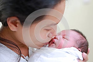 Closeup mother kissing infant baby in her arms in hospital after delivery room