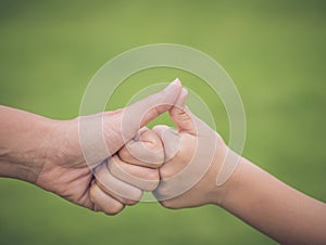 Closeup mother and son are hand thumb up in green background.