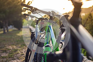 Closeup of mountain bikes standing leaned on a wall. Multiple bikes, later afternoon sunset golden hour. Friends resting their