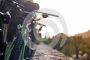 Closeup of mountain bikes standing leaned on a wall. Multiple bikes, later afternoon sunset golden hour. Friends resting their