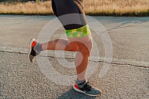 Closeup of muscular legs of a triathlete in professional equipment running early in the morning, preparing for a