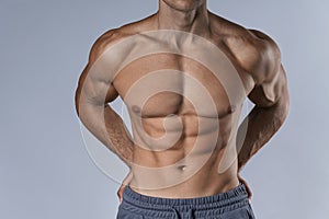 Closeup of muscular male torso against gray background