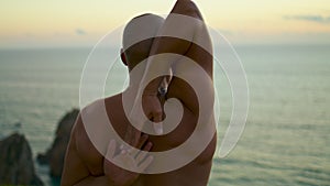 Closeup muscular man stretching arms at ocean sunset view. Athlete doing hand