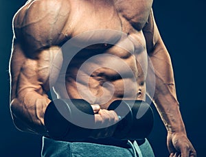 Closeup of a muscular young man lifting dumbbells