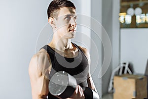 Closeup of a muscular young man lifting weights in the gym