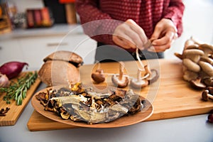 Closeup of mushrooms in a dish with woman stringing mushrooms