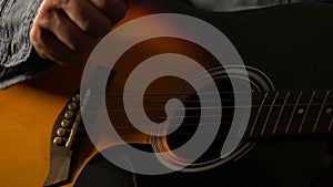 Closeup of musician playing acoustic guitar, feeling rhythm and composing music