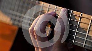 Closeup of musician's fingers strumming on acoustic guitar strings in the sunset