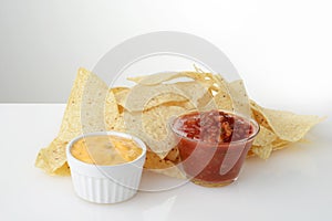 Closeup nacho chips with bowls of salsa and cheese