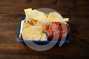 Closeup nacho chips with salsa in plastic tray