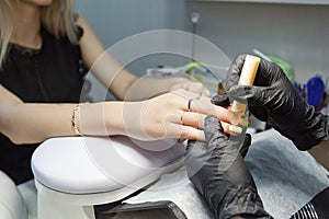 Closeup on nail master wearing black gloves making acrylic nails in salon. Concept of visiting beauty shop