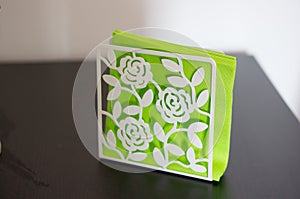 Closeup of a napkin holder with bright green paper napkins on the table