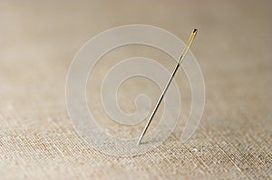 Closeup of needle on linen cloth background