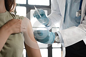 Closeup of a nervous woman and her doctor wearing face masks and getting a vaccine shot in a doctor& x27;s office.