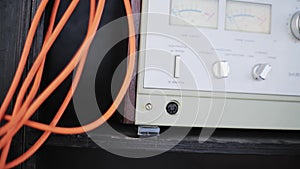 Closeup of new grey analog musical amplifier with connected orange cables.