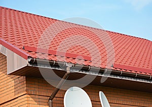 Closeup on new rain gutter system and roof protection from snow board. Red Roofing Construction.