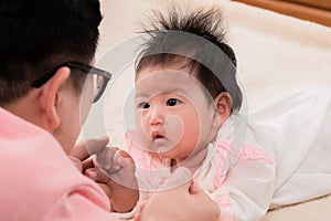 Closeup of newborn baby 3 months  eye contact with happy father with love and happiness, dad play with adorable daughter on bed,