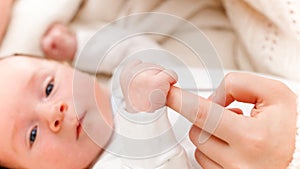 Closeup of newborn baby boy holding and catching mother's finger with little hands. Concept of family happiness and