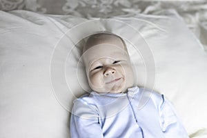 Closeup of a newborn baby lying on a bed in blue clothes