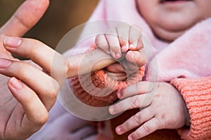 Closeup of a newborn baby`s hand holding mother`s finger.