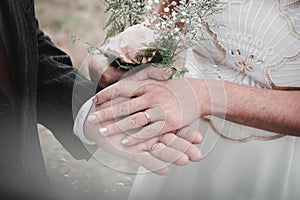 Closeup of a newly married couple holding hands in a park