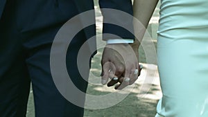 Closeup newly married couple walk together holding hands in city park