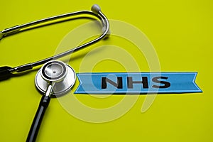 Closeup NHS with stethoscope concept inspiration on yellow background photo