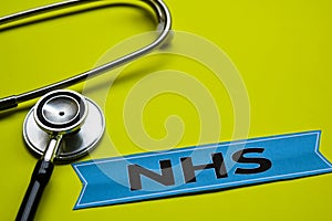 Closeup NHS with stethoscope concept inspiration on yellow background photo