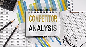 Closeup a notebook with text COMPETITOR ANALYSIS , business concept image on chart background