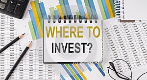 Closeup a notebook with text WHERE TO INVEST , business concept image on chart background