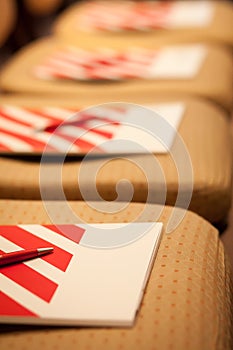 Closeup of notepad with pen for agenda on chairs in empty corporate conference room before business meeting