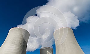 Closeup of nuclear power plant cooling towers belching out white plume of water vapor