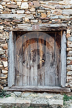 Closeup of the number one sign on the old weathered small wooden door of a stone building
