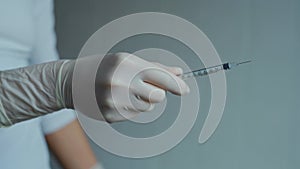 Closeup nurse hands in white sterile protective gloves takes off cap from insulin syringe needle.